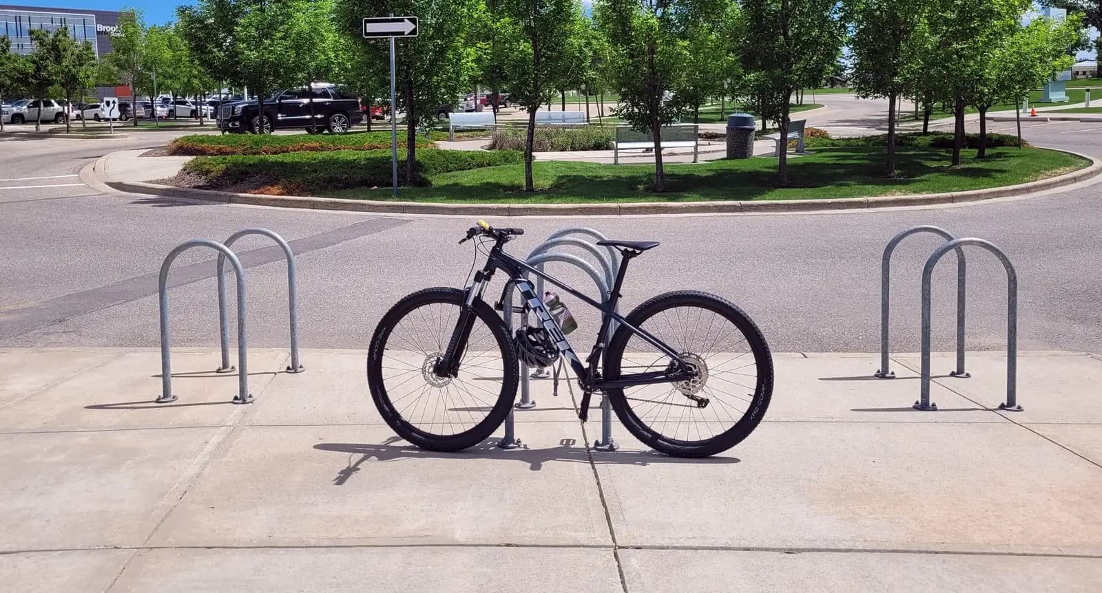 Supports à vélos en U inversé en acier galvanisé installés sur un trottoir près d'un parc paysagé