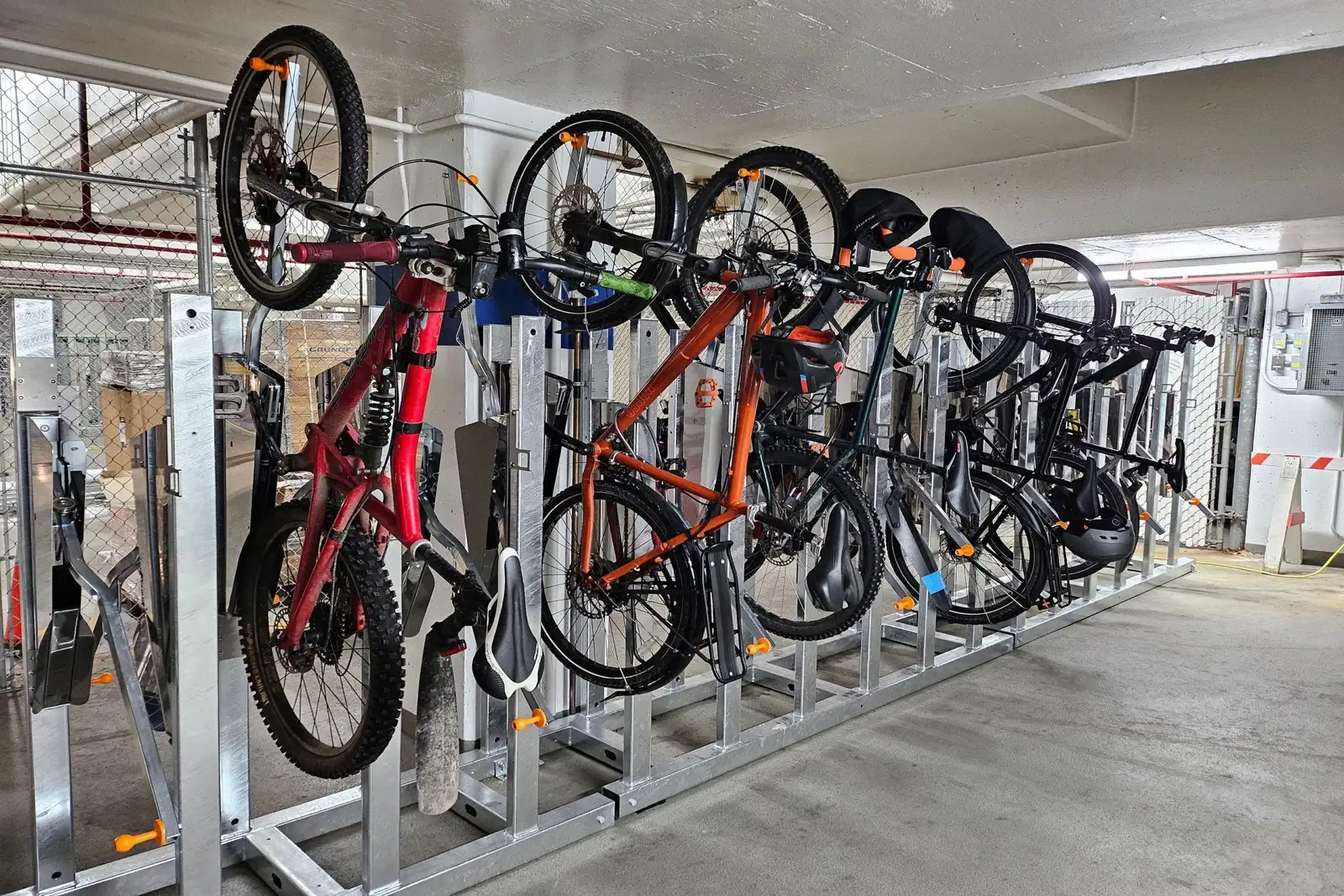 Supports verticaux à vélos avec vélos électriques et prises de recharge dans une salle à vélos de condo canadien